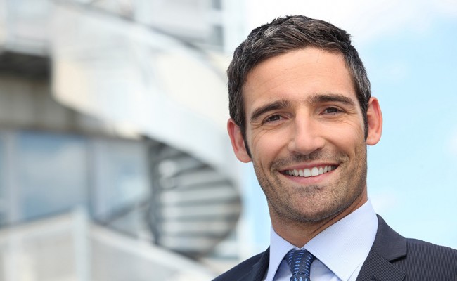 Smiling business man standing outside office building